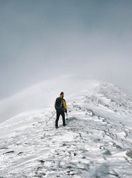 A lone hiker treks up a snow-covered mountain in Albania, embracing adventure and winter's chill.