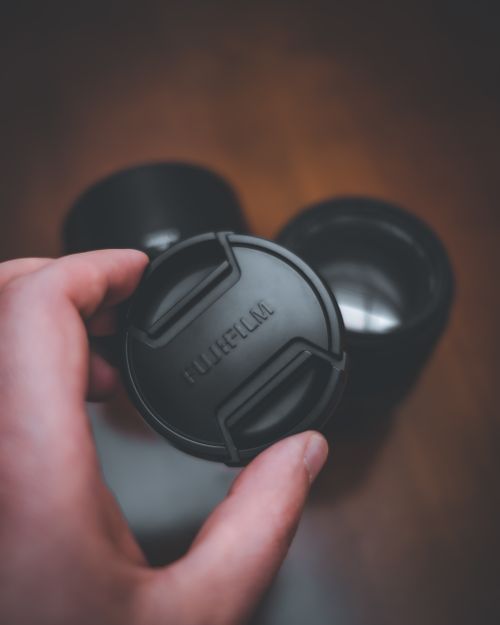 Free A detailed close-up of a hand holding a Fujifilm camera lens cap. Stock Photo