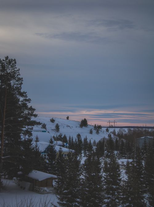 Free A serene winter landscape in Tatarstan, Russia, capturing a snow-covered hillside and trees at twilight. Stock Photo