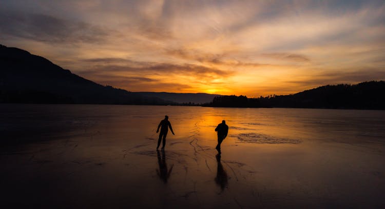 Silhouette Of Men Walking On Frozen Lake