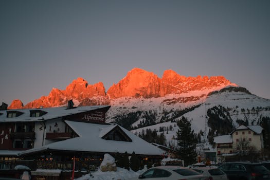 Scenic view of snow-covered mountains and hotel Alpenrose at sunset in Trentino's Dolomites.