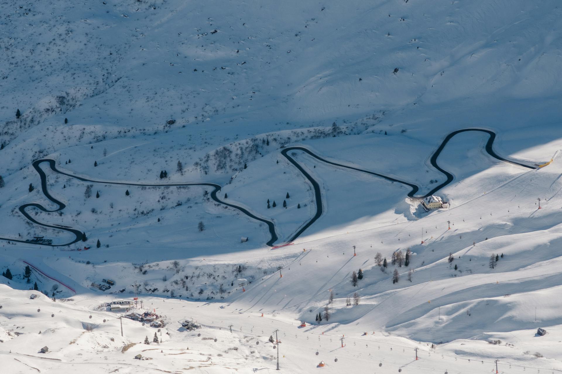 Winding snowy roads in Pozza di Fassa, Italy captured from above during winter.