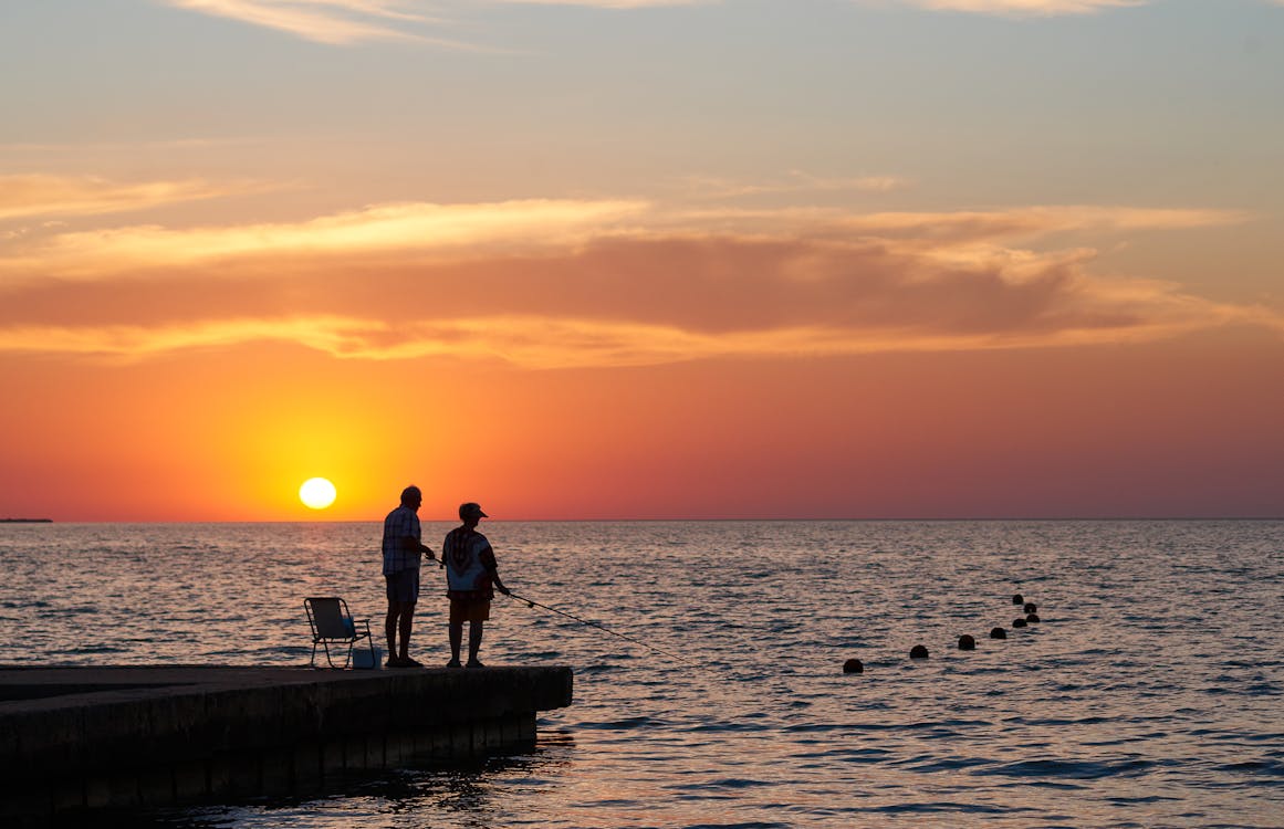 Silhouette of Two People Standing on Dock and Fishing during Sunset · Free  Stock Photo