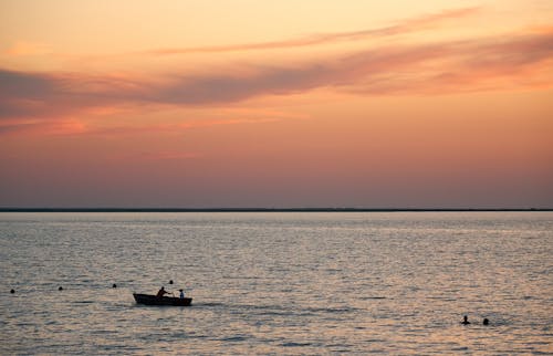 Silhouette of Two People Riding on Boat during Sunset