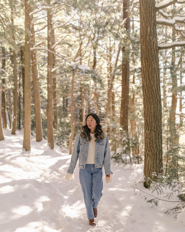 Woman In Jean Jacket Walking In Winter Forest