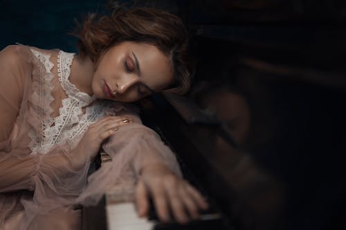 A Woman in a Sheer Top Leaning on a Piano