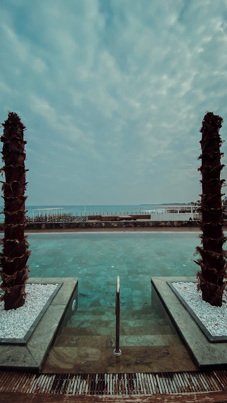 A Swimming Pool Under A Cloudy Blue Sky