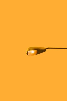 A close-up of a street lamp against a plain yellow background, emphasizing simplicity and modernity.
