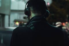 Person in headphones walking in urban setting. Nighttime relaxation and music immersion.