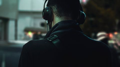 Person in headphones walking in urban setting. Nighttime relaxation and music immersion.