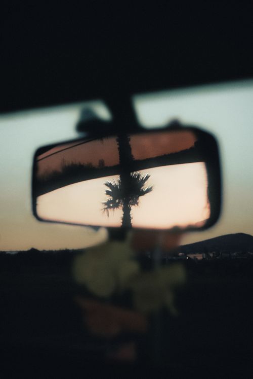Free Blurry reflection of a palm tree during sunset in a car's rearview mirror. Stock Photo