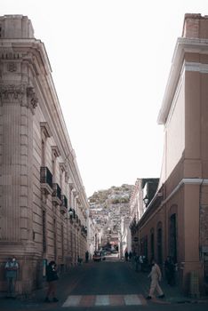 Charming city street with classic architecture and people walking on a sunny day.