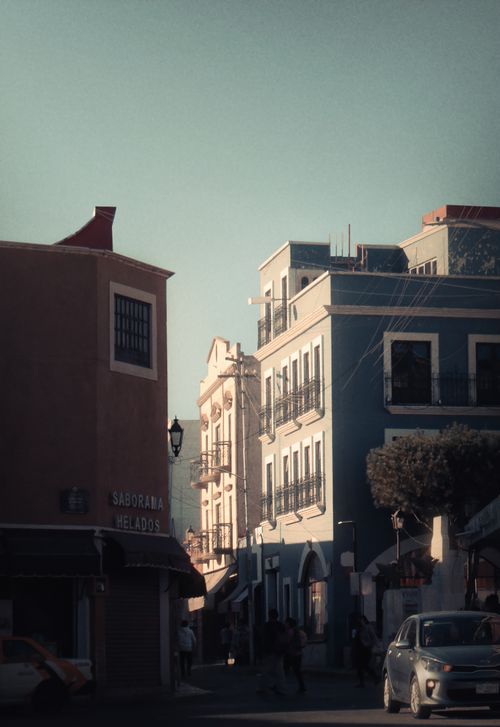 Free Capture of a quaint urban street at dusk, featuring historic buildings and pedestrians. Stock Photo