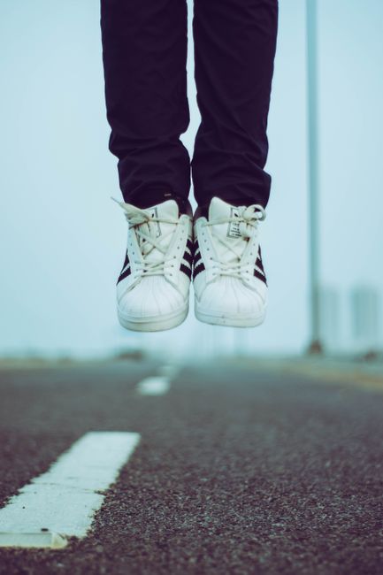 Dynamic shot of sneakers jumping on a deserted urban road, symbolizing freedom.