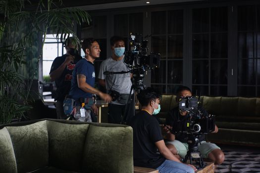 Film crew setting up camera equipment for indoor scene. Teamwork and filmmaking in action.