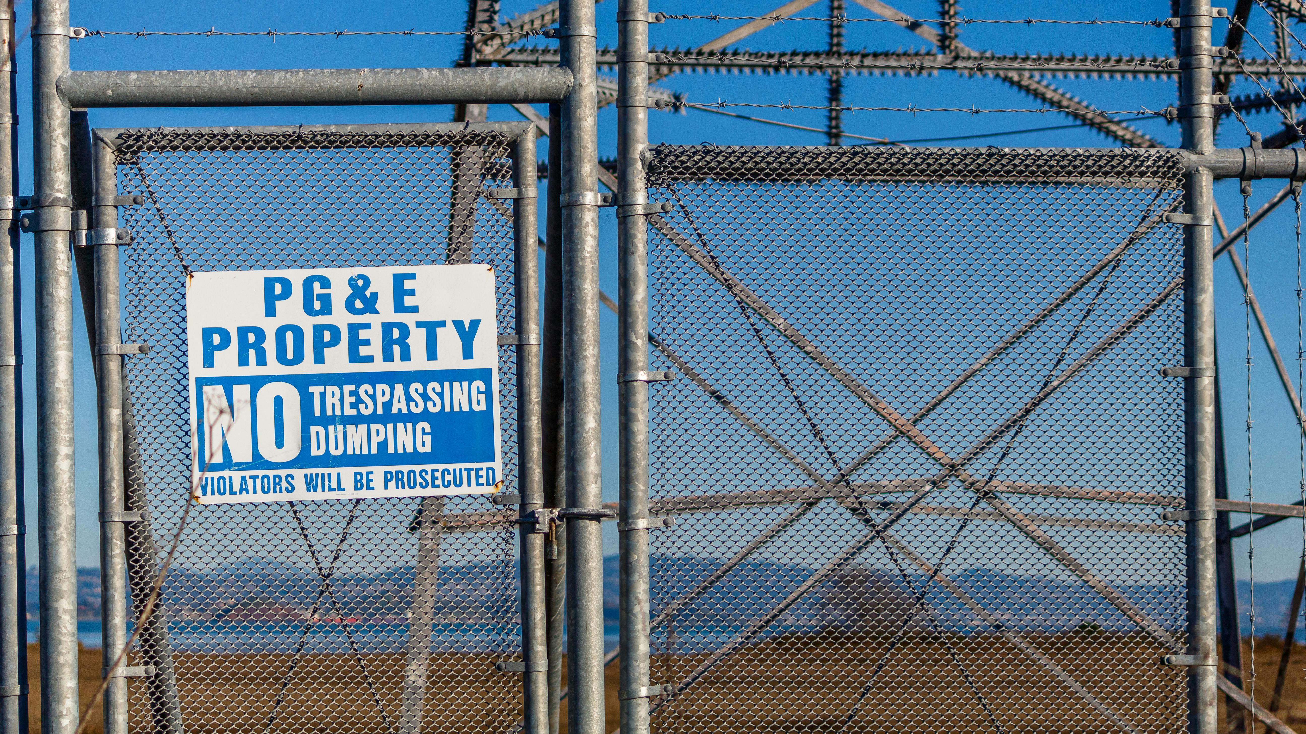 Metal fence with no trespassing sign warning at a utility property.