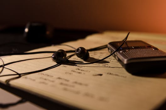 Earbuds and recorder on a notebook, perfect for studying and recording ideas.