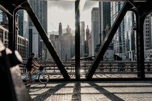 Man Riding a Bicycle on the Bridge Among Skyscrapers