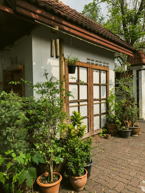 Free Cozy bungalow surrounded by lush greenery and elegant potted plants. Stock Photo