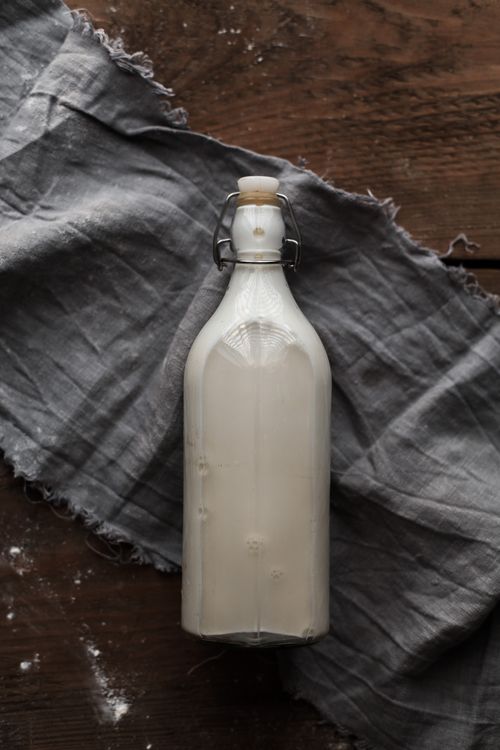 Free Flat lay of a vintage milk bottle on rustic wooden table with cloth fabric. Stock Photo