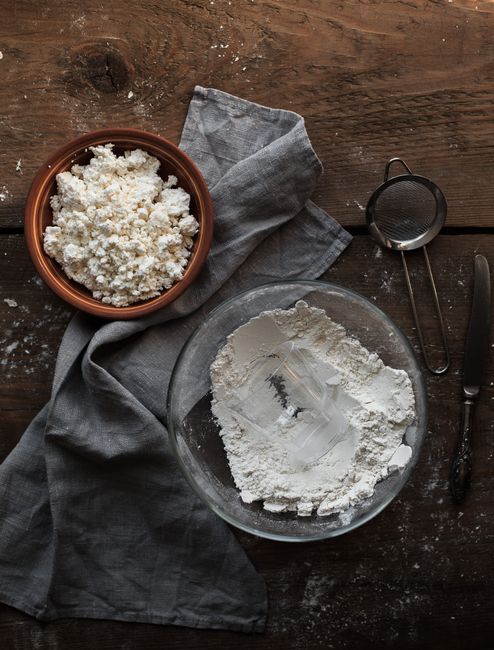 Top view of flour and cottage cheese on a rustic wooden table, perfect for baking inspiration.