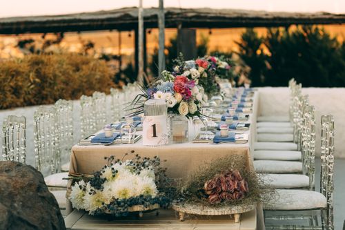 Free Beautifully arranged outdoor wedding table with floral centerpiece under a warm sunset. Stock Photo