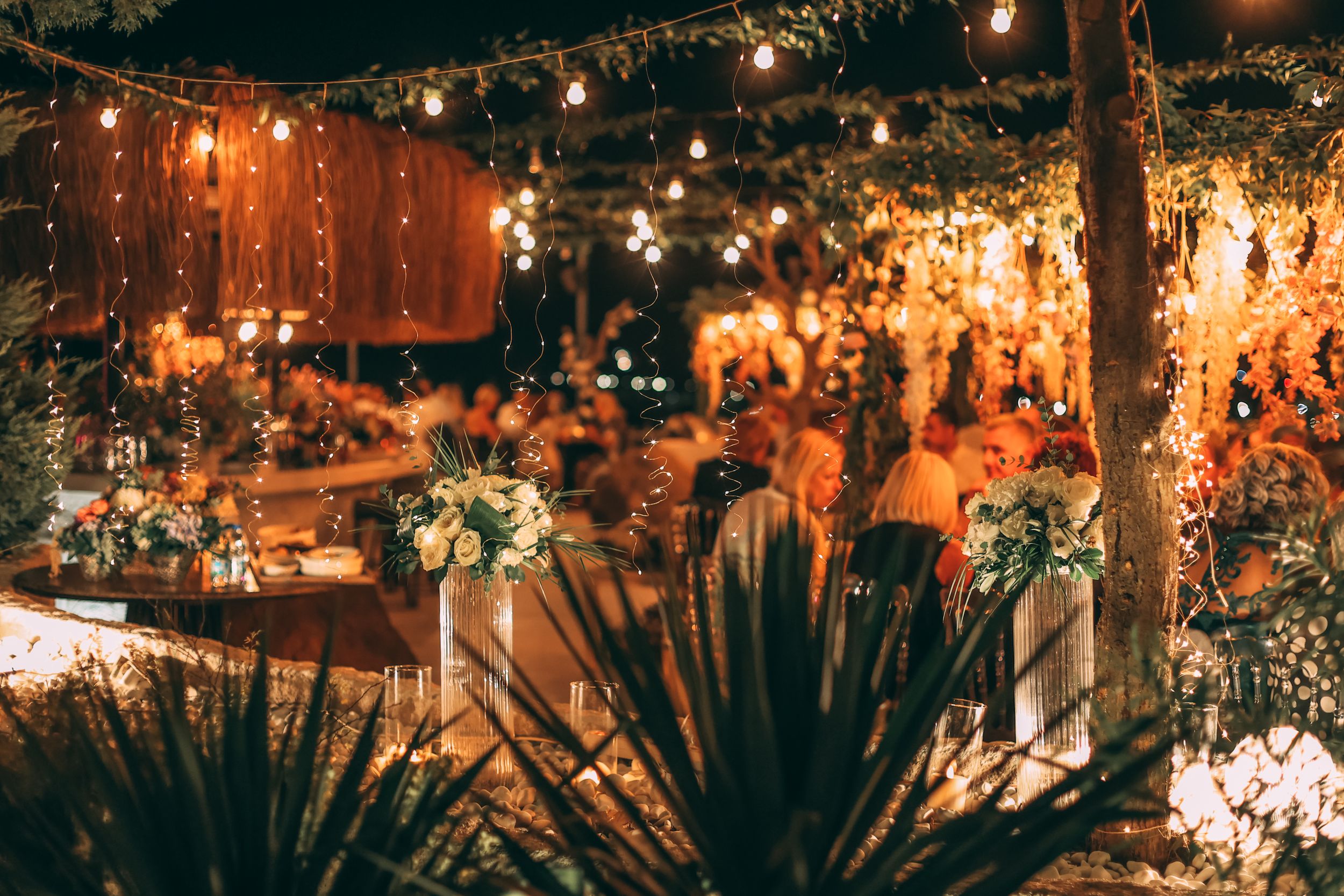 Réception en soirée en extérieur, guirlandes lumineuses et décoration florale, jardin élégant