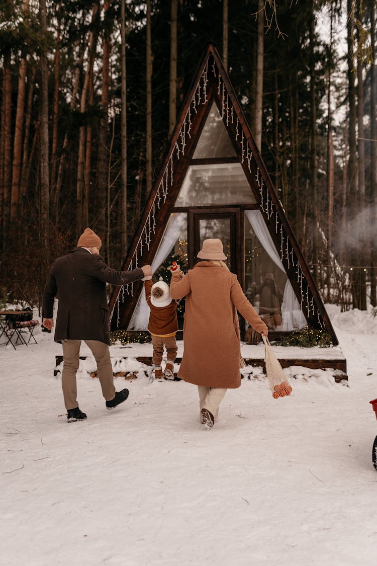 Couple Walking Back To Cabin Lifting Up Their Child