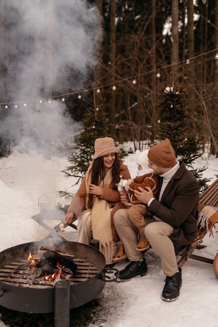 Couple With Child Sitting By Campfire