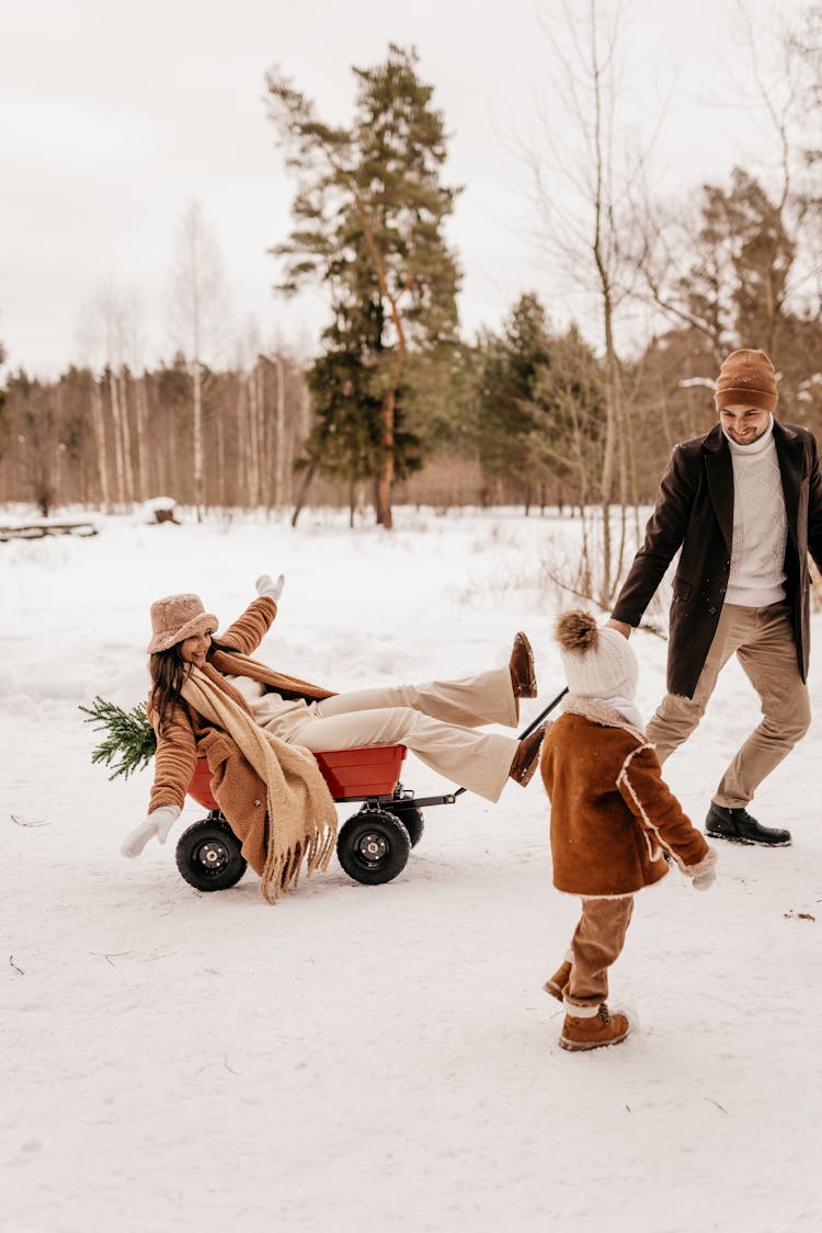 Man Pulling Woman Through Snow On Cart