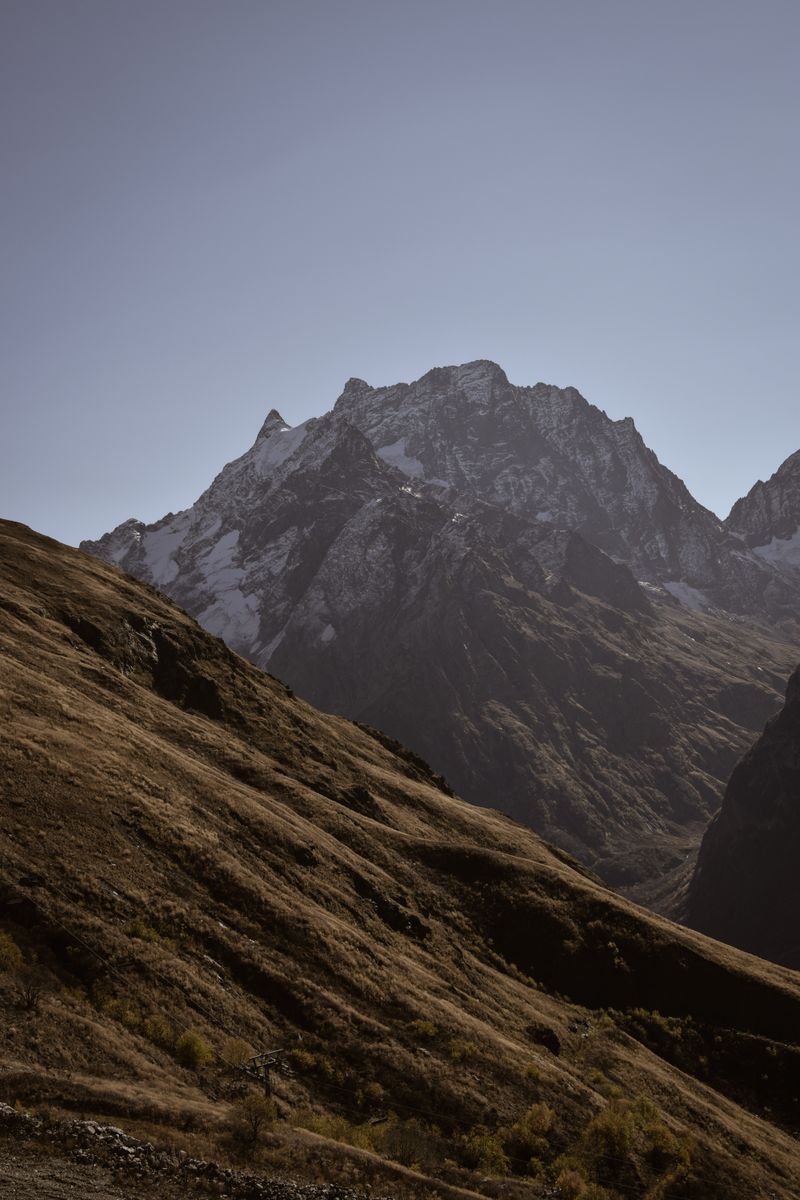 A breathtaking view of a towering mountain range with a clear, bright sky, perfect for nature lovers and adventurers.