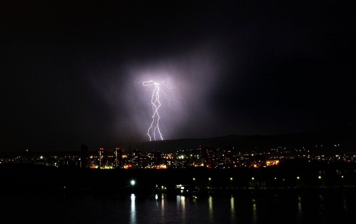 Lightning in Dark Sky above Illuminated City