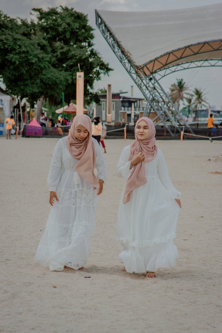 Two Young Women In White Traditional Dresses And Pink Head Kerchiefs