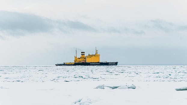 A yellow icebreaker ship sails through frozen waters near Saint Petersburg, Russia, in winter.