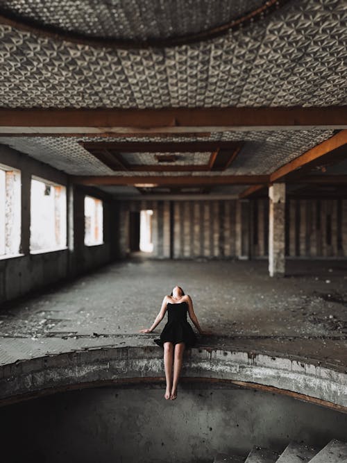 Woman with Bare Feet Wearing a Black Dress Posing in a Decay Architecture