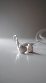 Detailed close-up of white earphones on a white surface, highlighting modern audio technology.