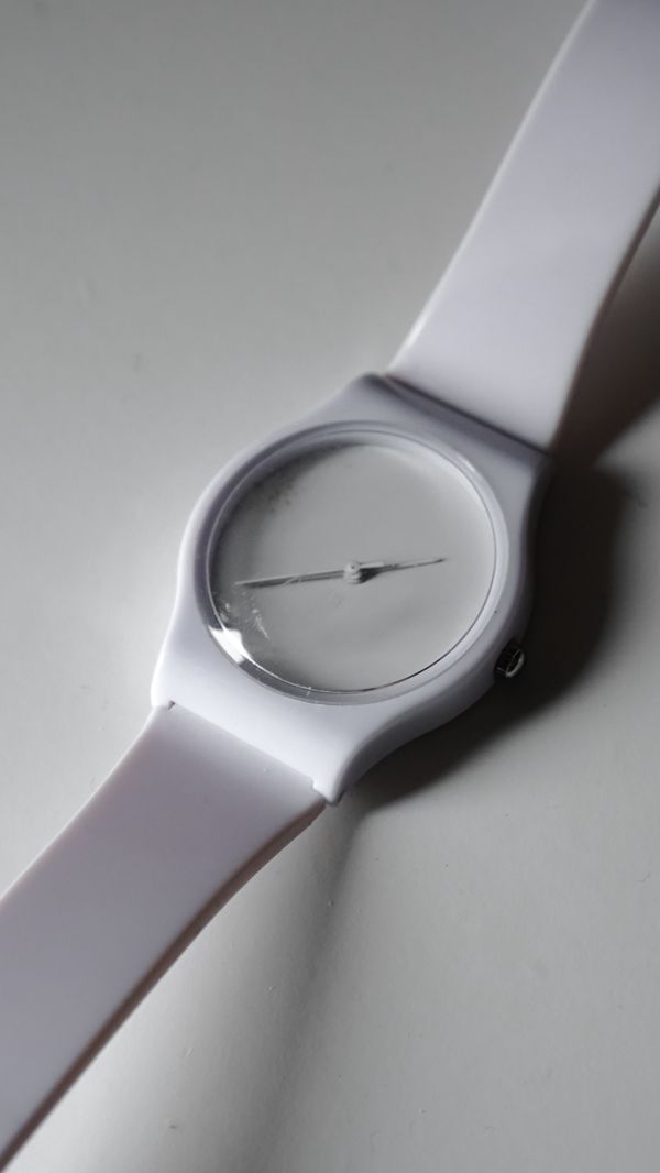 Minimalist white wristwatch on a neutral surface — photo by Nathan J Hilton on Pexels