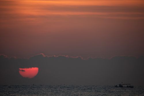 Free Tranquil sunset scene in Yangyang, South Korea featuring the horizon and a silhouetted boat. Stock Photo