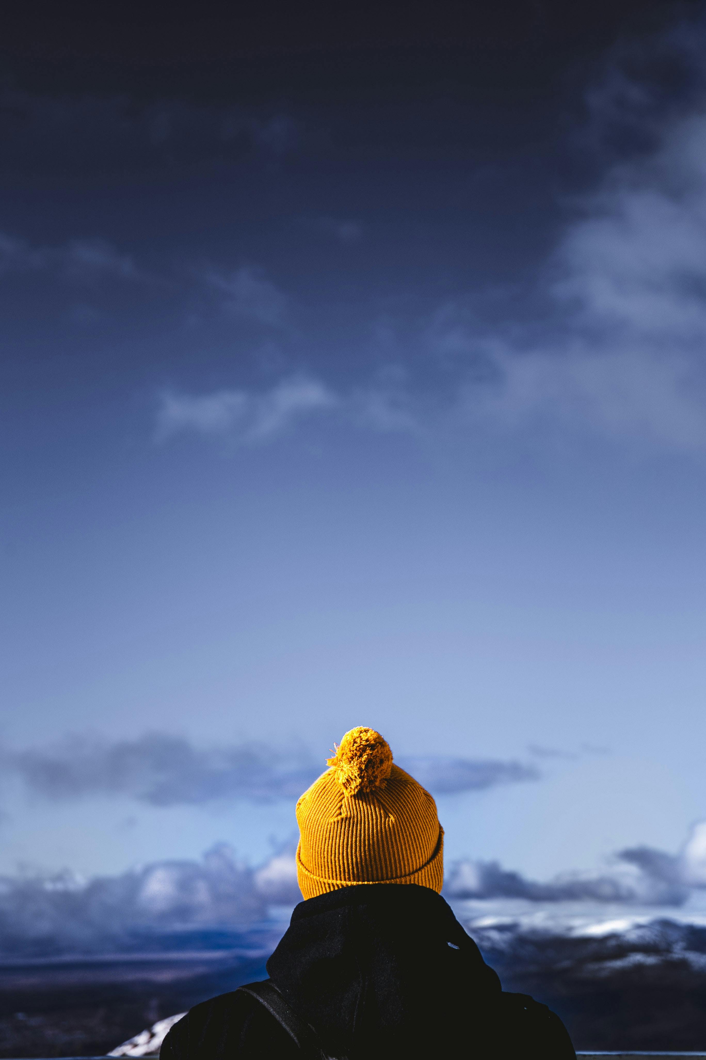 A person in a yellow winter hat gazing at the vast blue sky in Dina Huapi, Argentina.