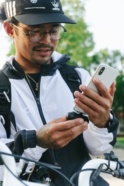 Free Man in Black Cap and Jacket Holding a Cellphone Stock Photo