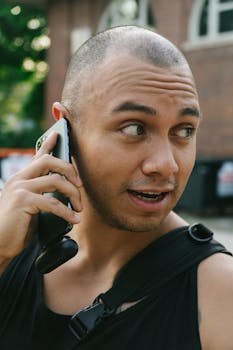 Bald man having a conversation on his smartphone in an outdoor setting.