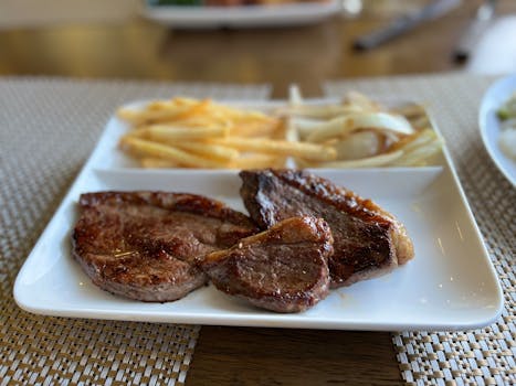 A mouth-watering grilled steak with crispy french fries served on a modern white plate in Gunma, Japan.