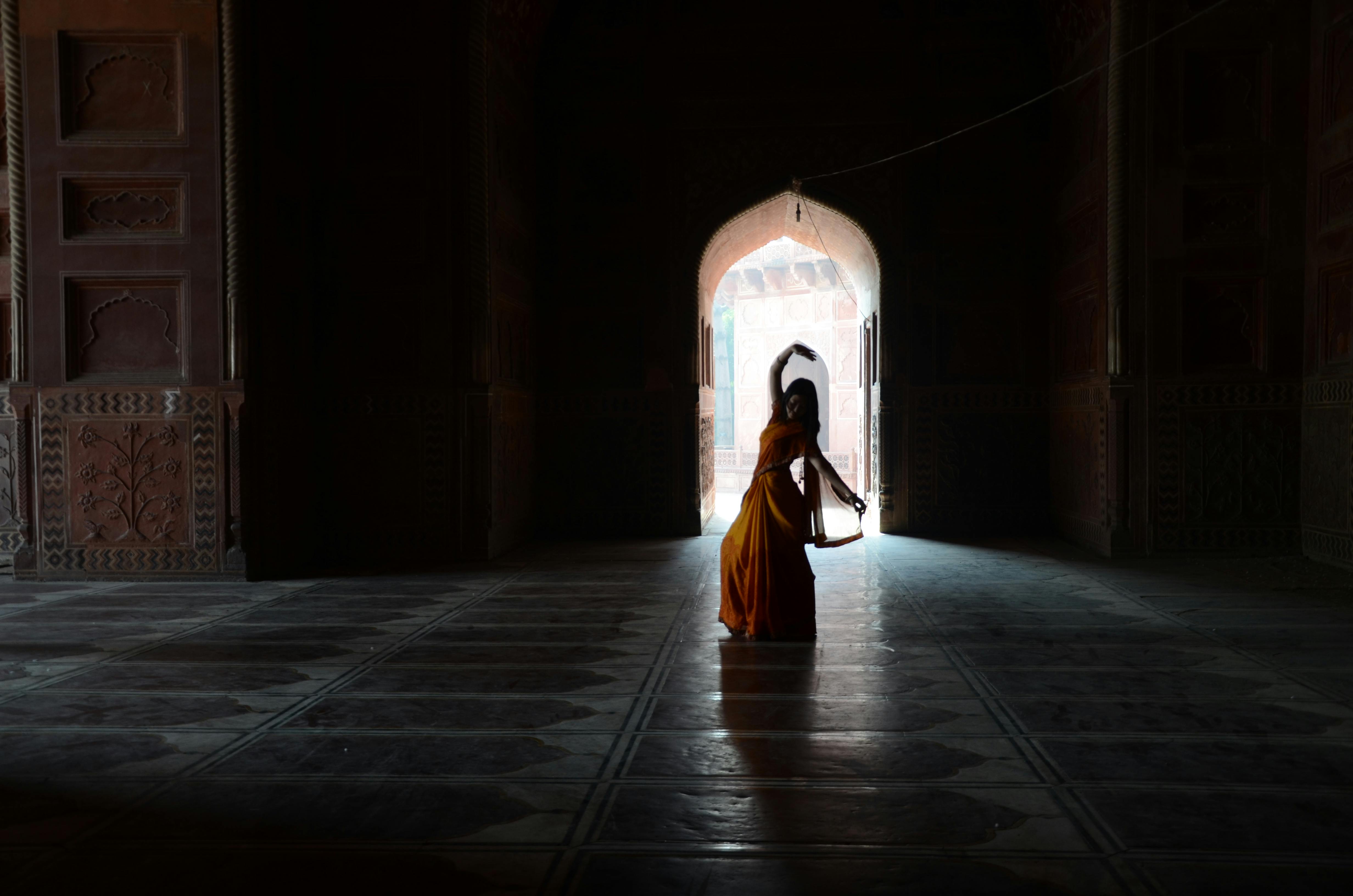 在历史悠久的寺庙内，一名穿着传统服装的妇女跳舞的剪影
