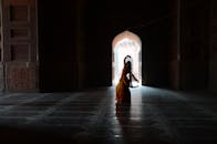 在历史悠久的寺庙内，一名穿着传统服装的妇女跳舞的剪影