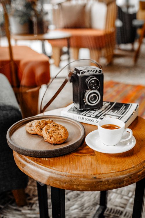Free A vintage camera and coffee setup in a cozy cafe setting, offering a warm ambiance. Stock Photo