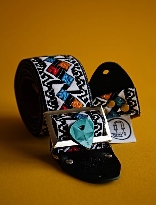 Free Close-up of a colorful guitar strap with a plectrum on a yellow background. Ideal for music themes. Stock Photo