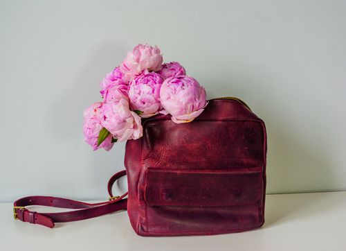 Free Elegant pink peonies elegantly spilling out of a vintage leather bag, showcasing a chic floral arrangement. Stock Photo