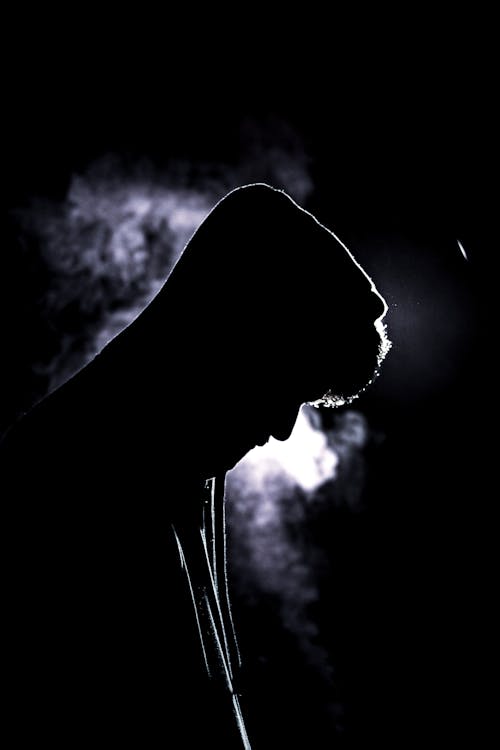 Man in Hood in Smoke on Black Background