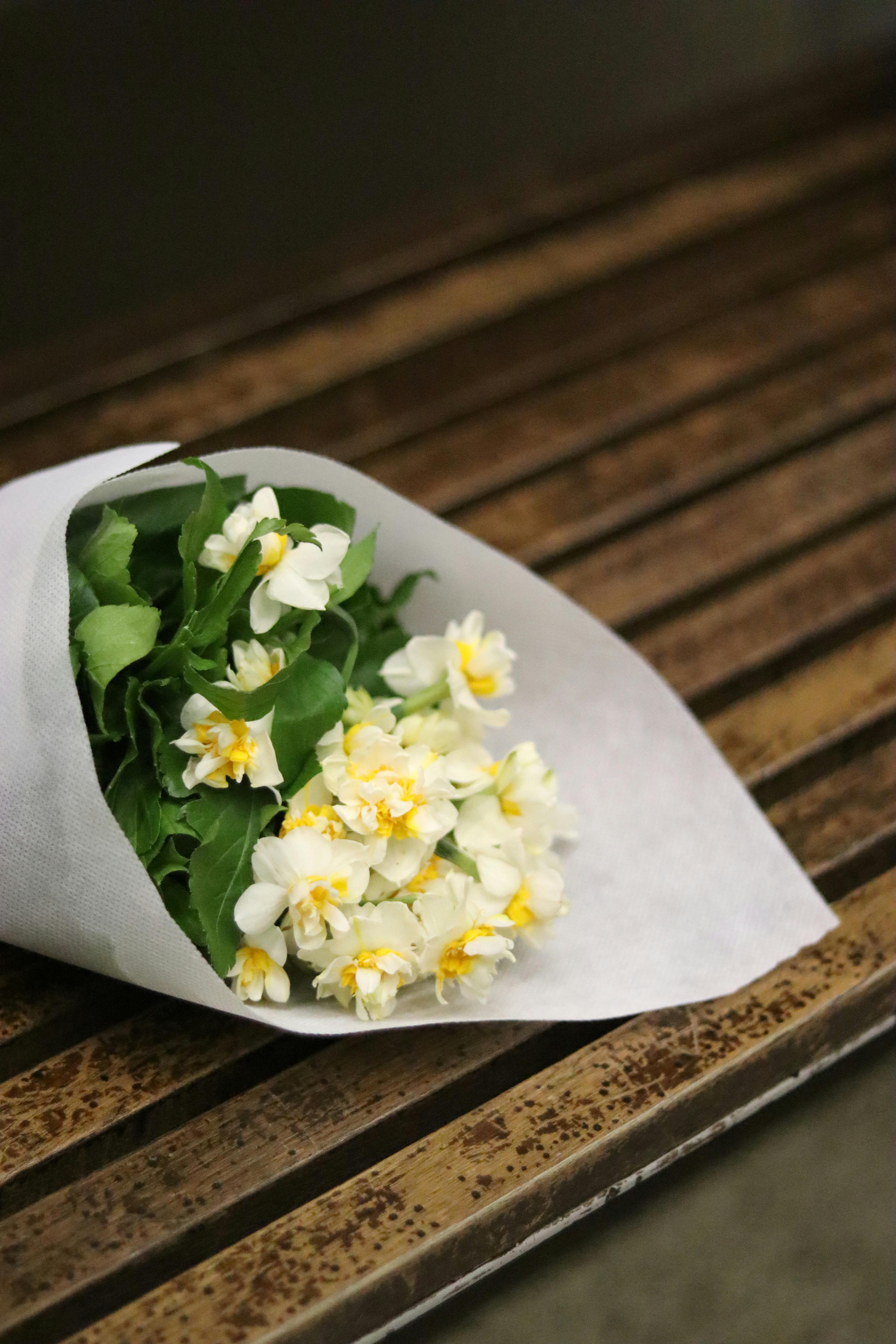 white flowers wrapped in paper laying on bench