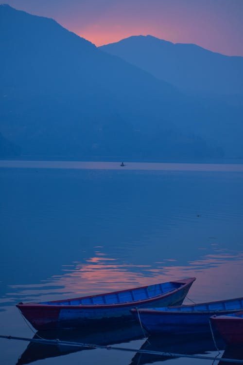 View of Boats Moored on the Shore and Mountains in the Background at Sunset
